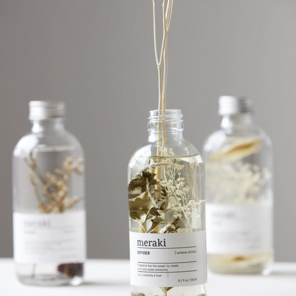 Dekoratívny aróma difuzér vo forme sklenenej fľaštičky s aromatickou tekutinou a ratanovými tyčinkami, ktoré uvoľňujú vôňu v miestnosti.