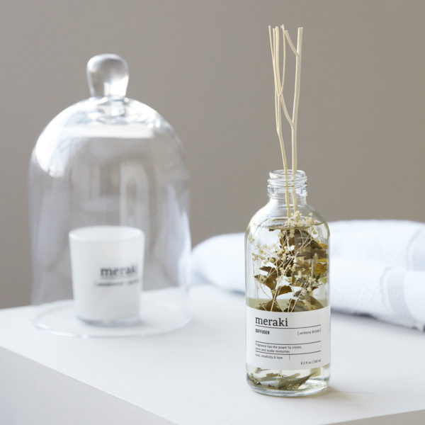 Dekoratívny aróma difuzér vo forme sklenenej fľaštičky s aromatickou tekutinou a ratanovými tyčinkami, ktoré uvoľňujú vôňu v miestnosti.