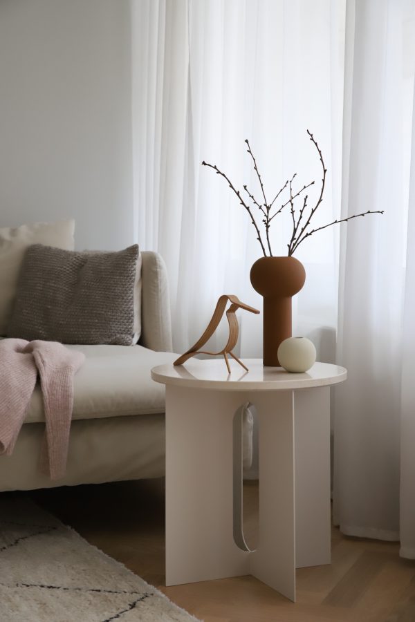 Moderná ručne robená keramická váza s úzkou vysokou nohou v tvare valca zakončená klasickým guľovitým tvarom v béžovej farbe.