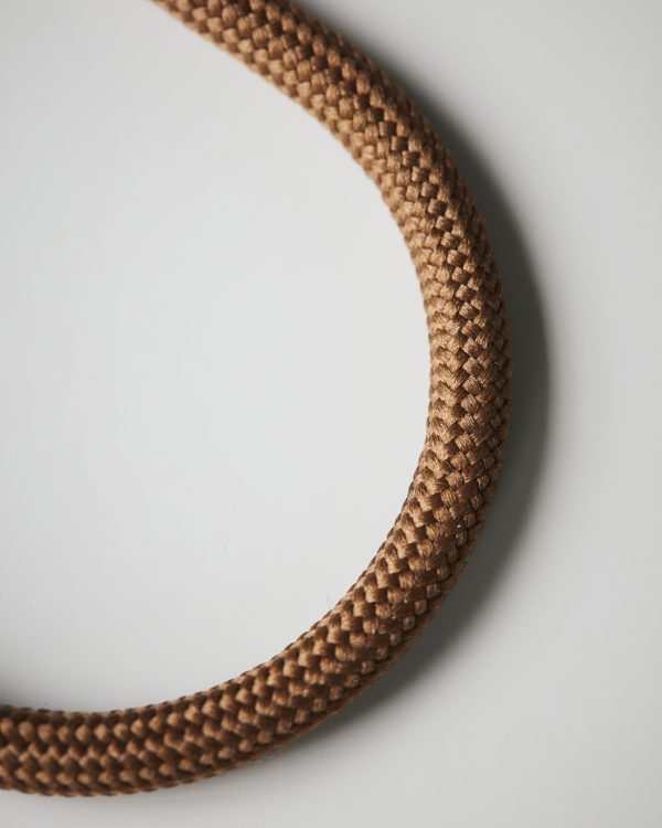 Minimalistický okrúhly kovový vešiak potiahnutý nylónom v hnedej farbe.
