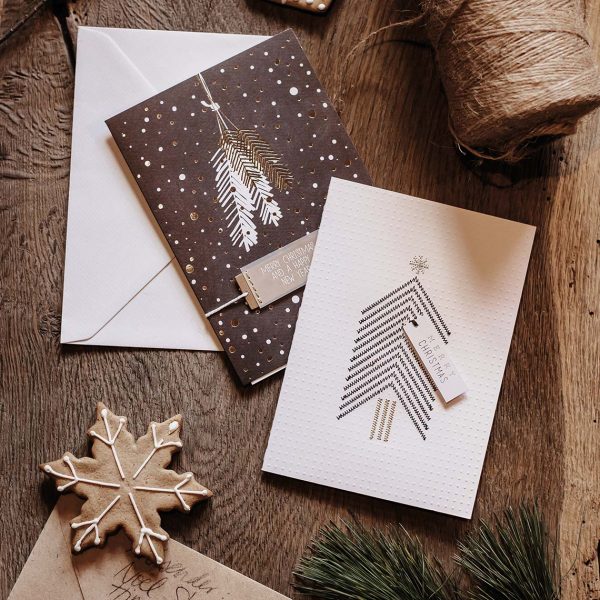 Otváracia vianočná pohľadnica v bielej farbe s čiernym vianočným stromčekom so zlatým kmeňom a nápisom "MERRY CHRISTMAS".