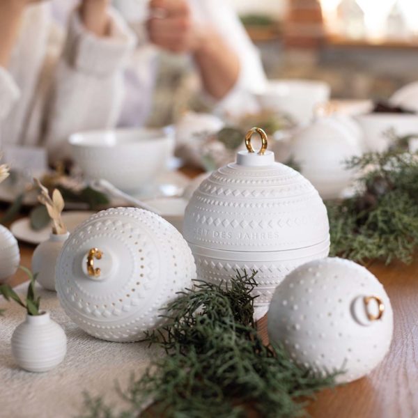 Biela vianočná ozdoba vo forme gule s reliéfnym povrchom s dierkami a LED svetlom oveľkosti cca. 10 cm.